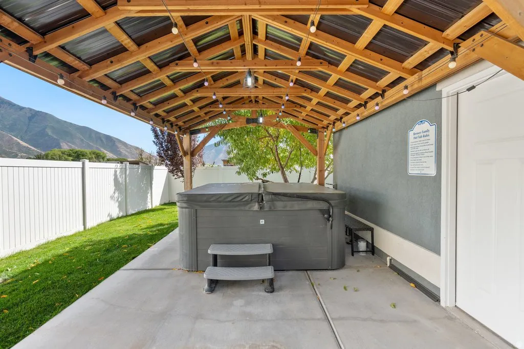 Covered patio featuring a hot tub, string lighting, and a slatted wood ceiling