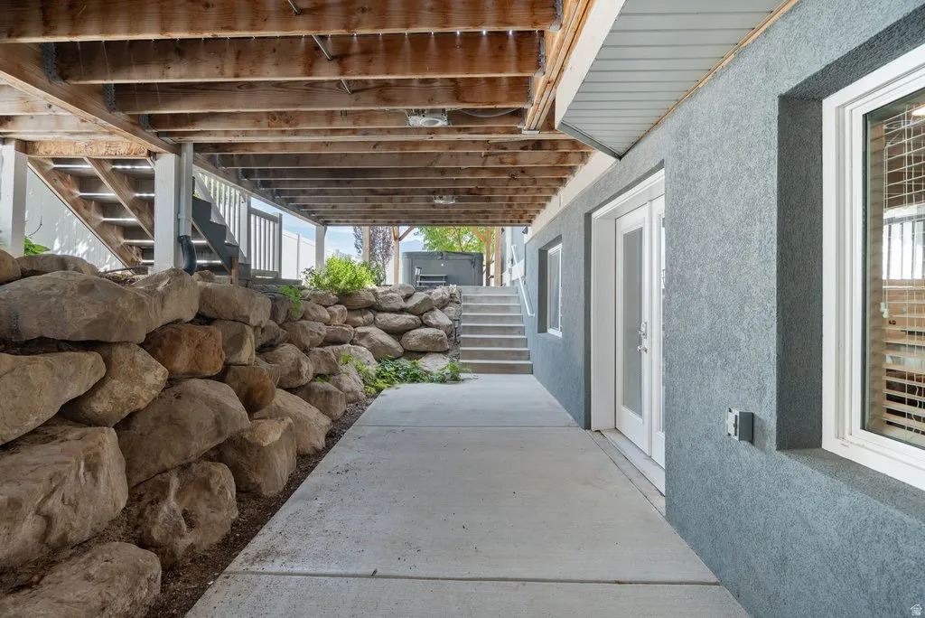 Concrete patio with an exposed aggregate retaining wall, under a wood-beamed deck