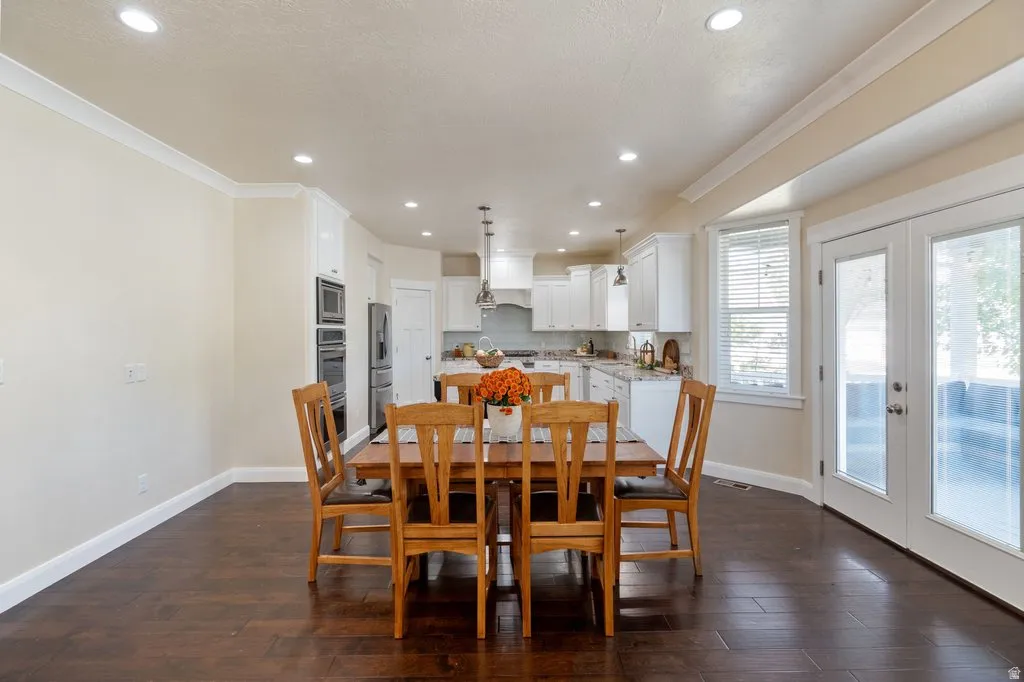 Hardwood-finish flooring, recessed lighting, white crown molding, dual pane glass doors, and a well-appointed kitchen with white cabinetry