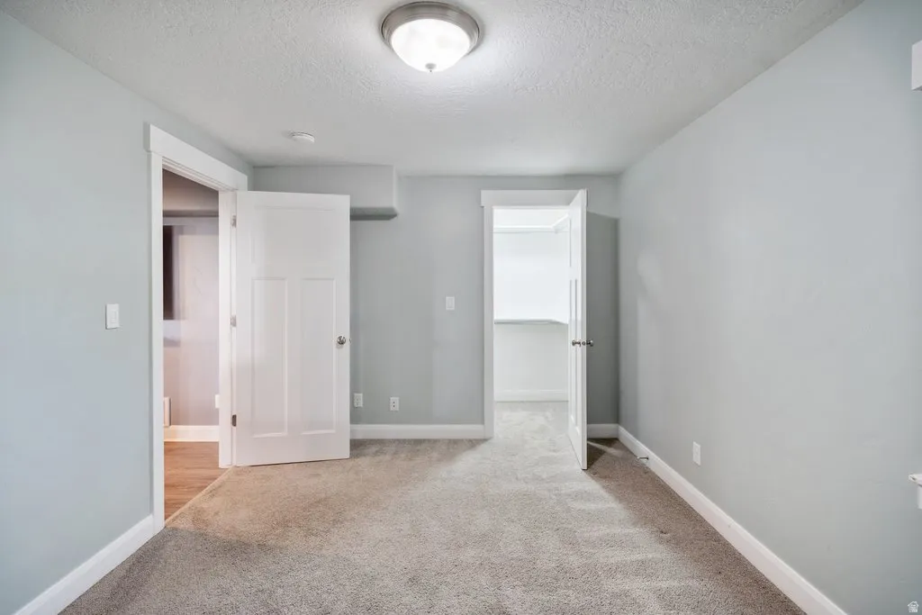Light gray wall paint, textured ceiling, flush mount ceiling light fixture, white trim, and gray carpet flooring
