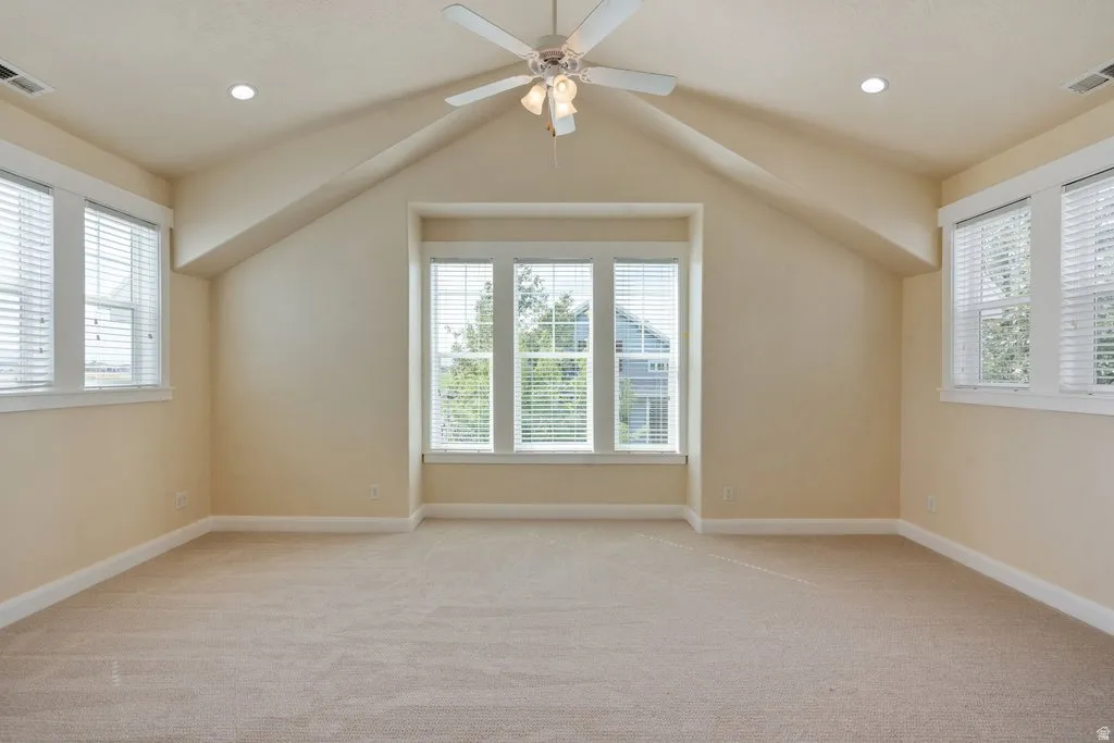 Vaulted ceiling with a ceiling fan, recessed lighting, carpet flooring, and multiple windows with blinds