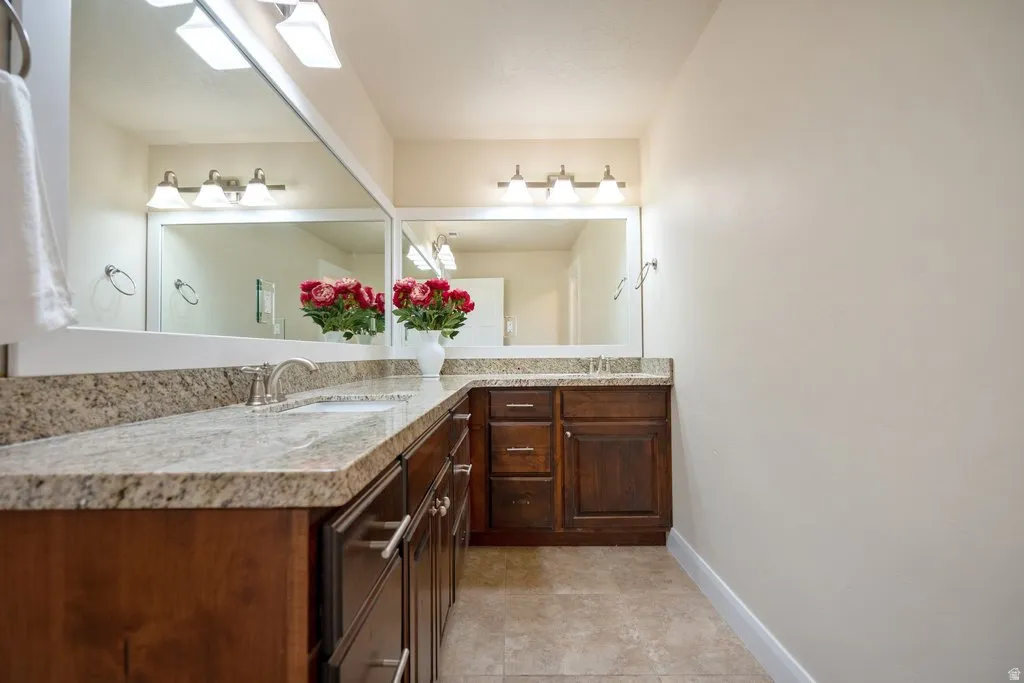 Dual vanity featuring wood cabinetry, stone countertops, and integrated sinks