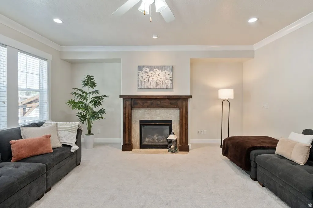 Fireplace featuring a wood mantel and stone surround, recessed lighting, crown molding, and a ceiling fan
