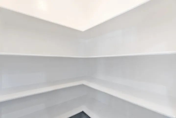 Recessed built-in shelving with multiple levels, white paint finish, and dark flooring
