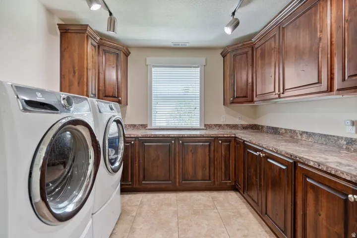 Expansive counter space, extensive wood cabinetry, tiled flooring, and window with blinds