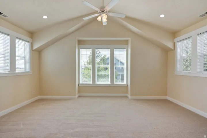 Vaulted ceiling with a ceiling fan, recessed lighting, carpet flooring, and multiple windows with blinds