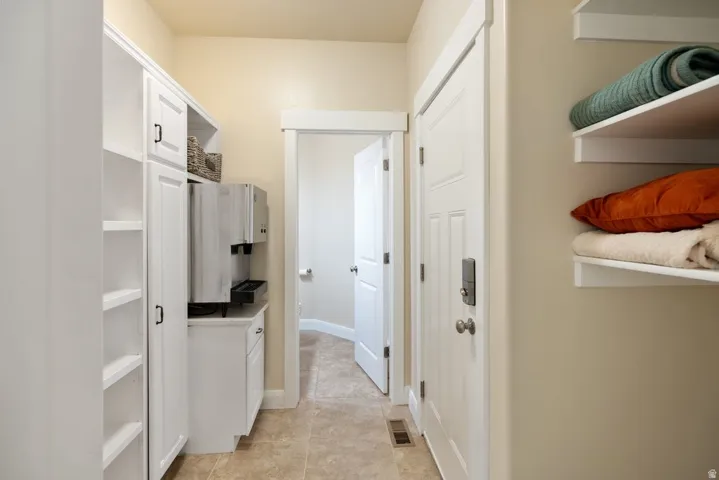 Tile flooring with built-in cabinetry, open shelving, and solid panel doors