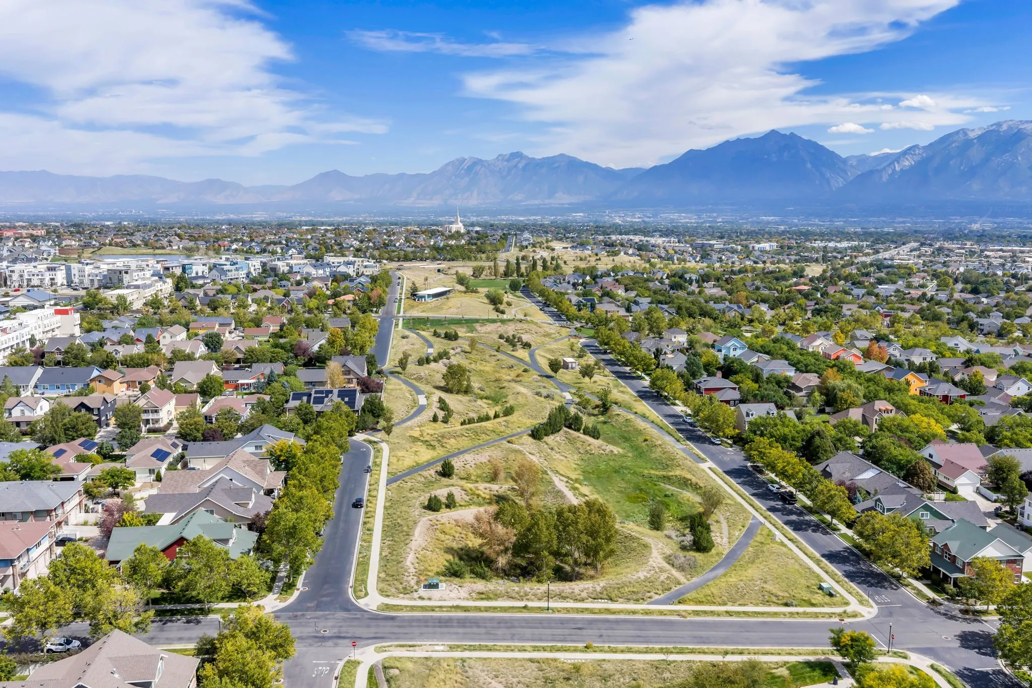 Aerial perspective showcasing a residential area with varied housing styles, surrounded by green spaces and paved pathways
