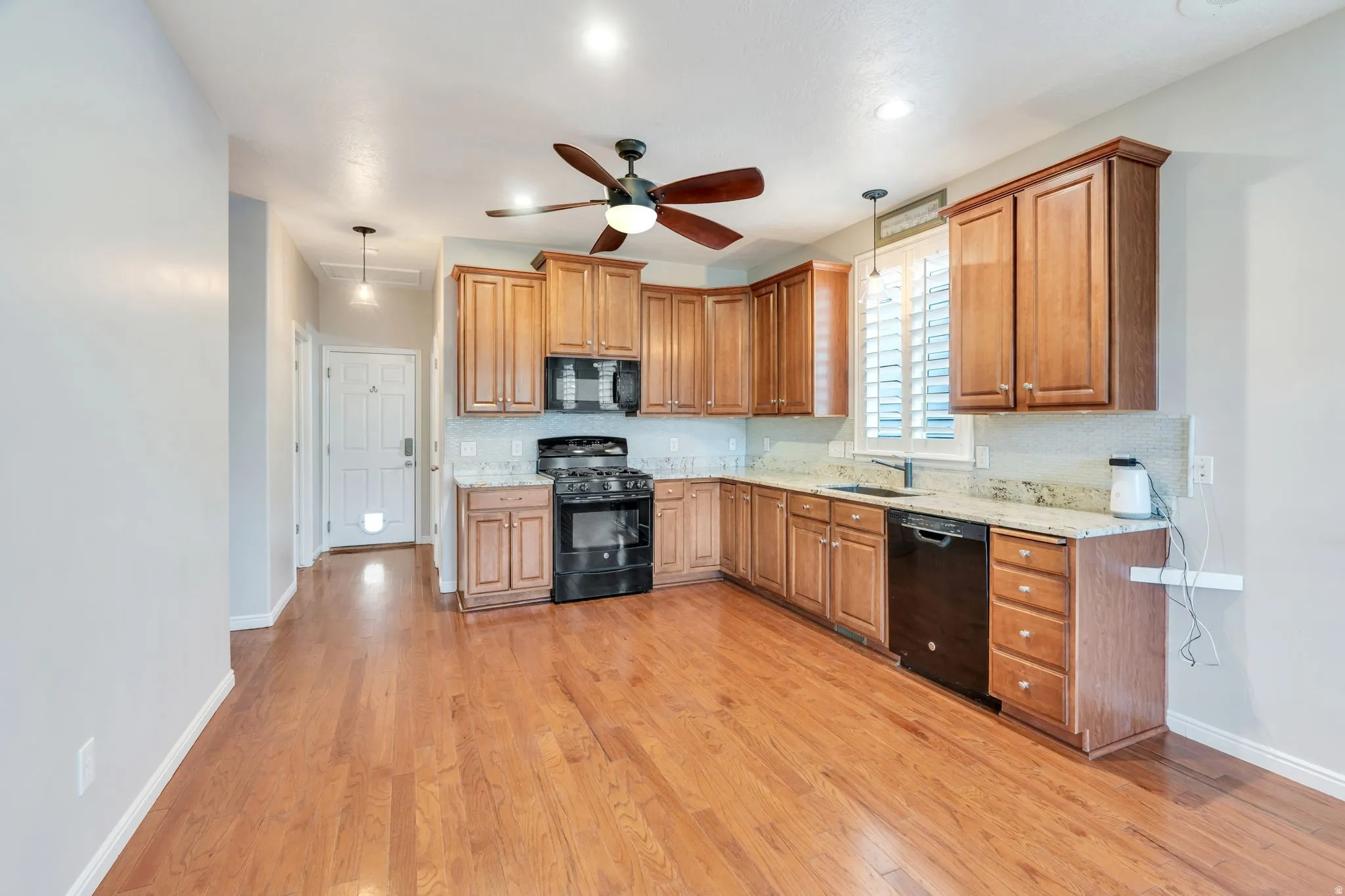 Kitchen featuring wood-finish flooring, recessed lighting, wood cabinetry, stone countertops, and a ceiling fan