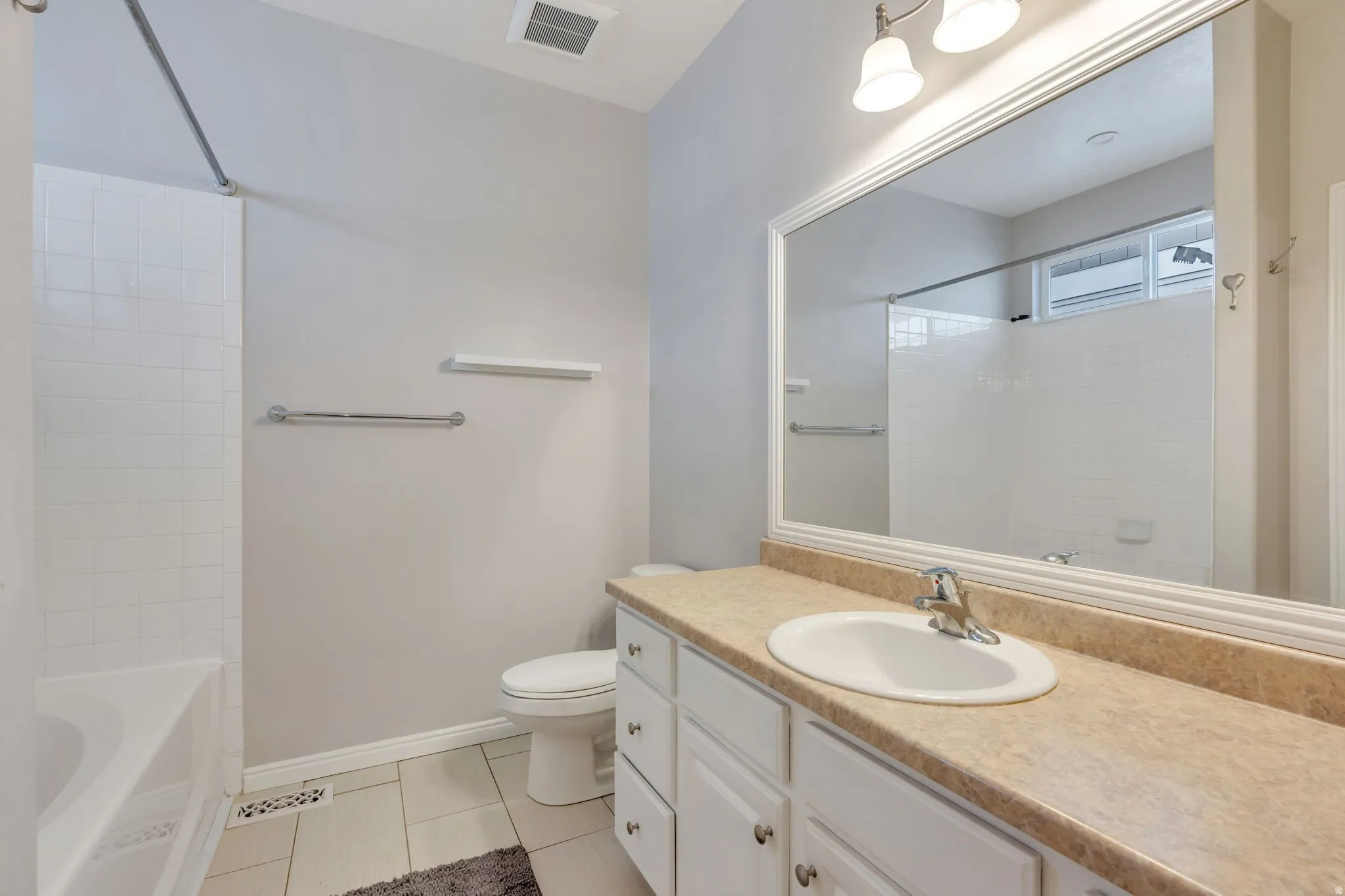 Bathroom with a single vanity, white cabinetry, integrated sink, and a large wall-mounted mirror