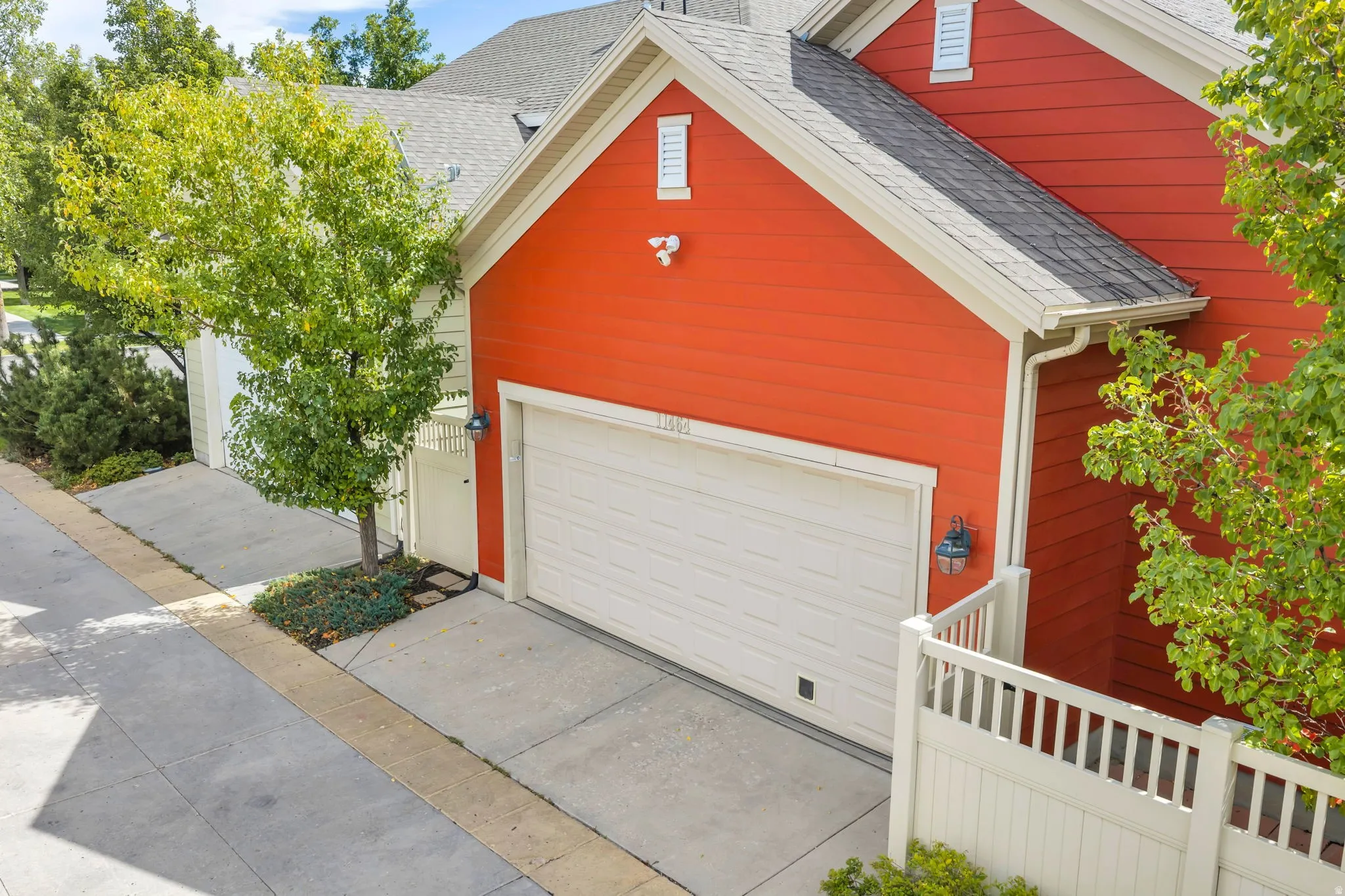 Red siding exterior with white trim, a single garage door, and outdoor wall sconces