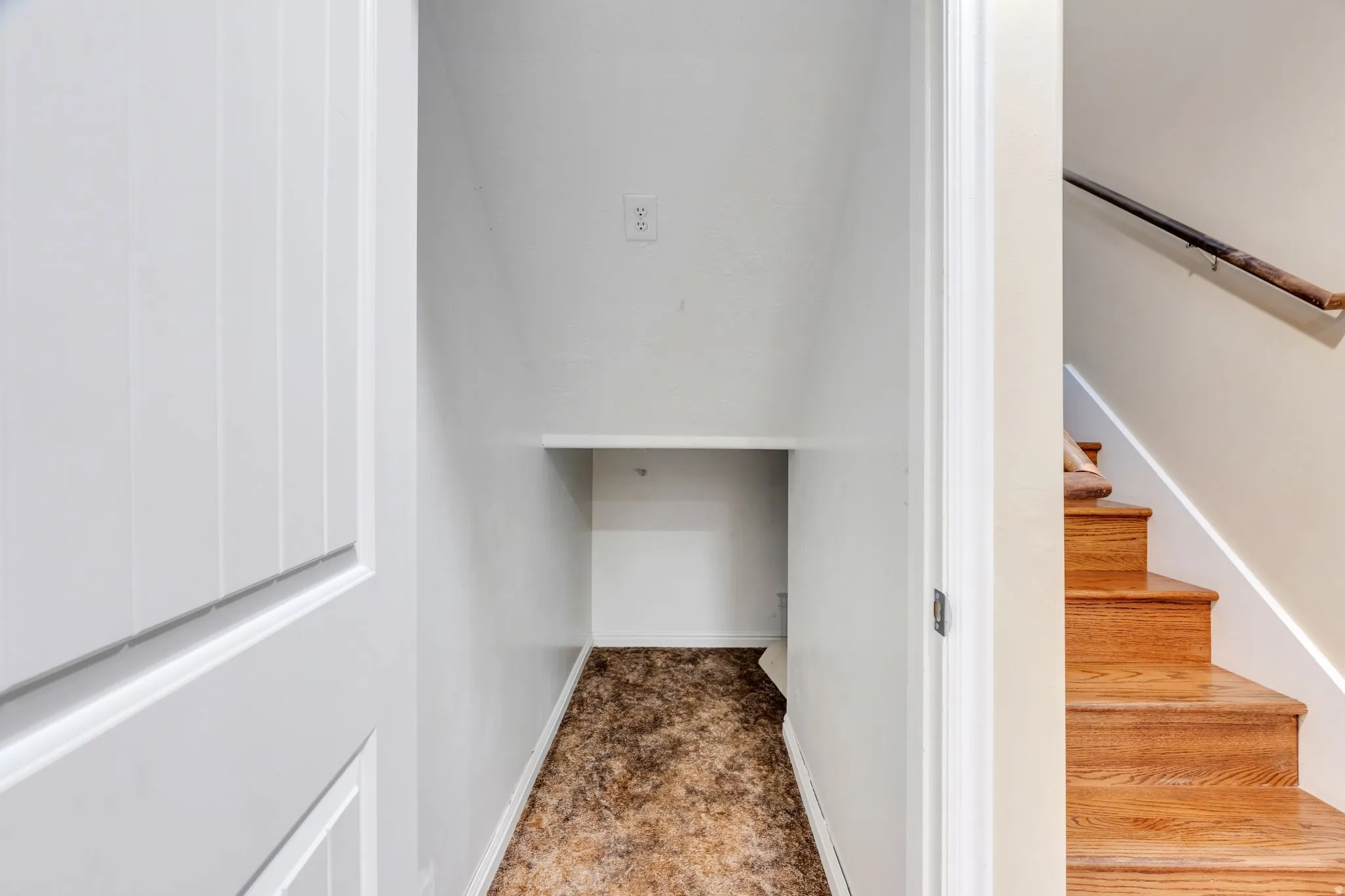 Under-stair storage area with a built-in shelf and wood-finish stairs