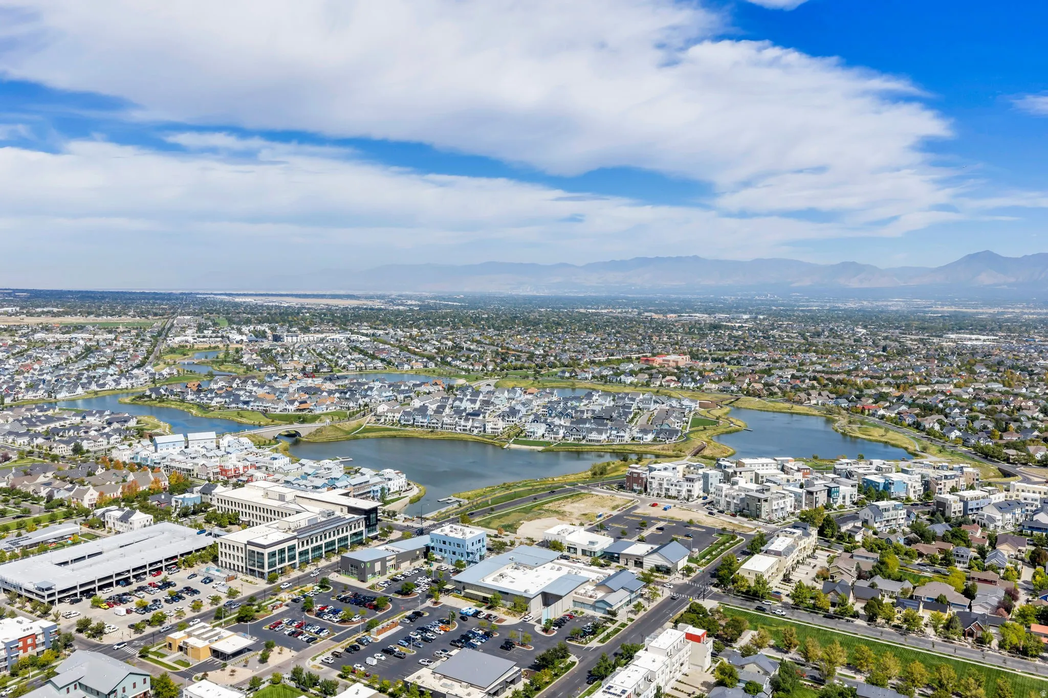 Lakeside community featuring multiple bodies of water, residential architecture, commercial structures, and distant mountains
