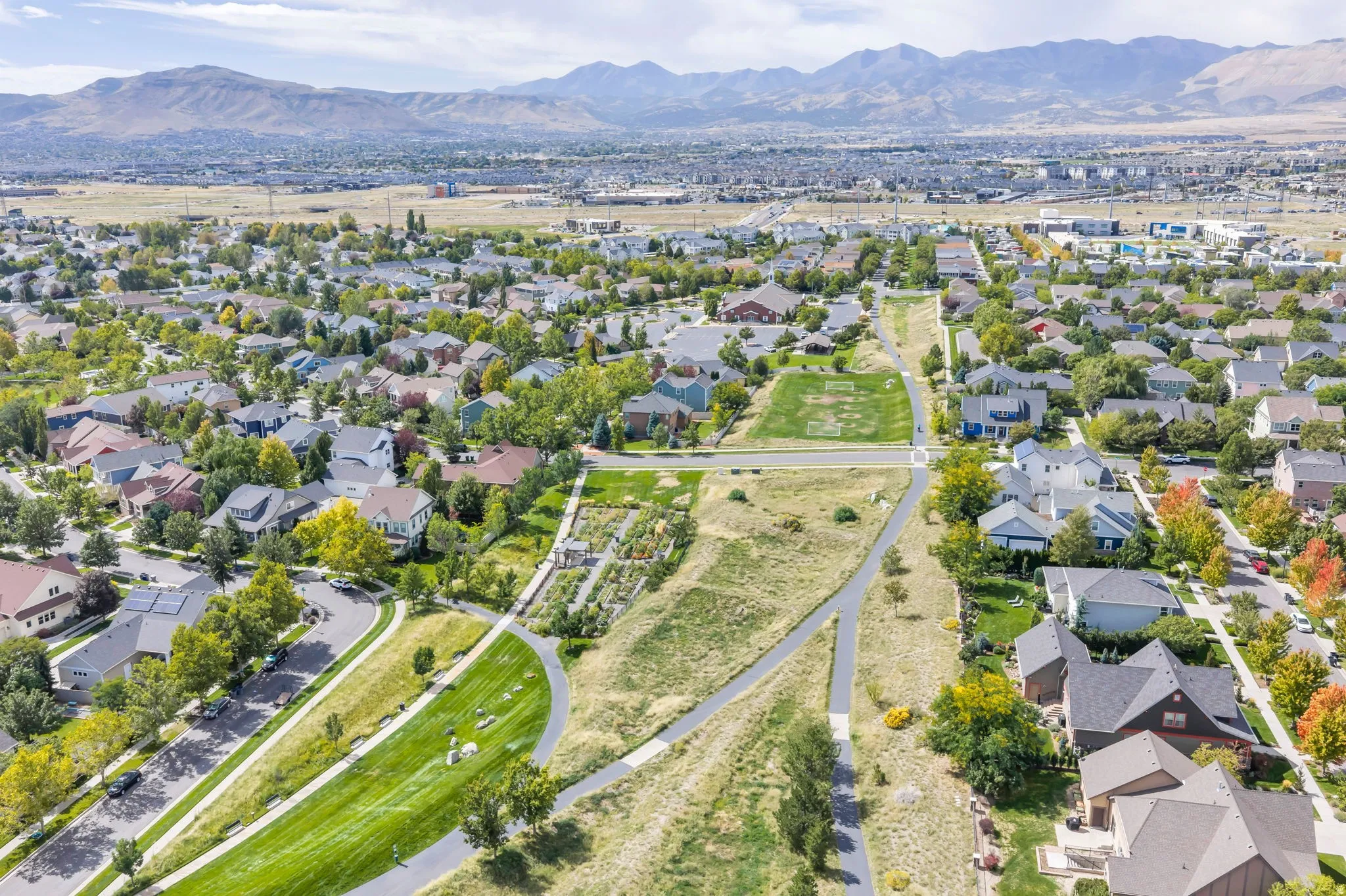 Expansive residential neighborhood with mature trees, paved pathways, and distant mountain backdrops