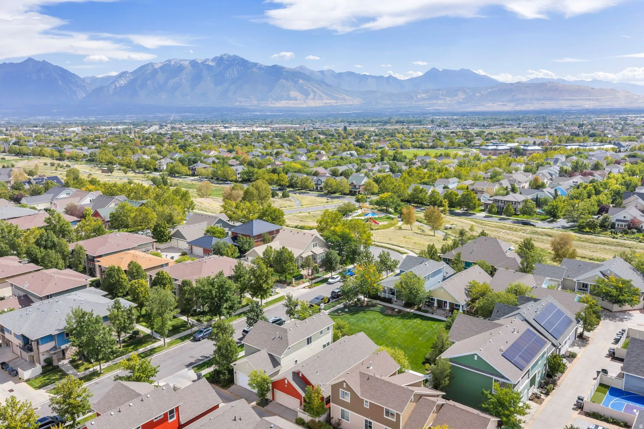 Residential neighborhood with mountain scenery, green spaces, and solar panel installations