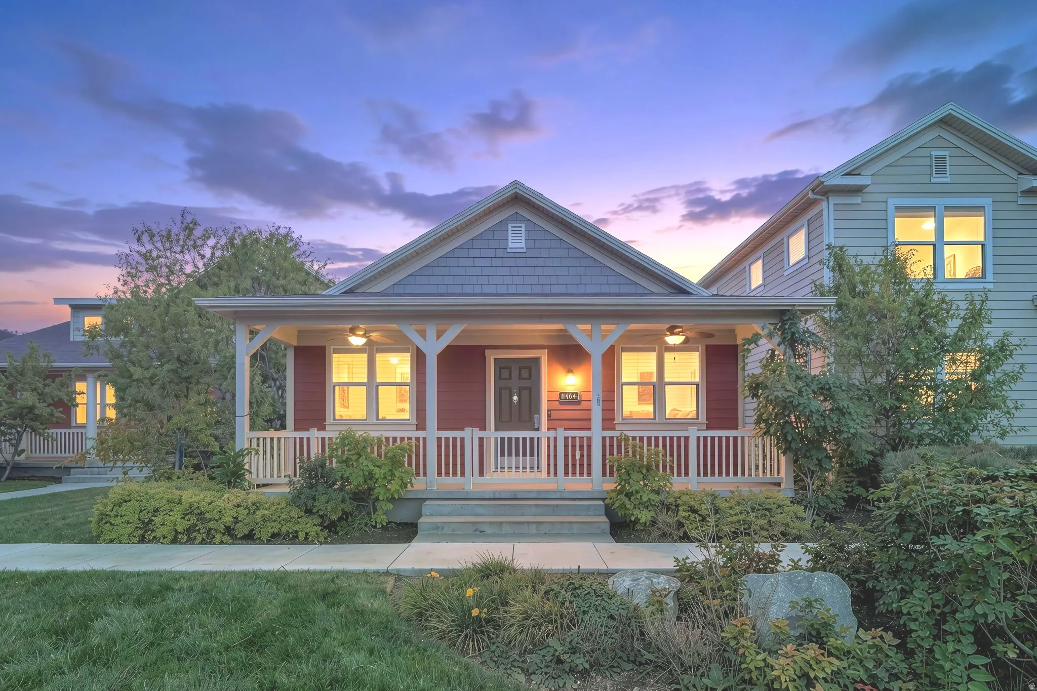 Red siding exterior with gray shake accent, covered front porch with white railing, and landscaped front yard