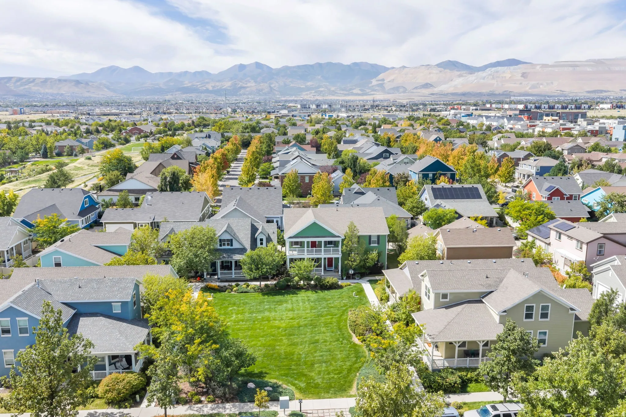 Residential community with a variety of architectural styles, mature trees, mountain backdrop, and green spaces
