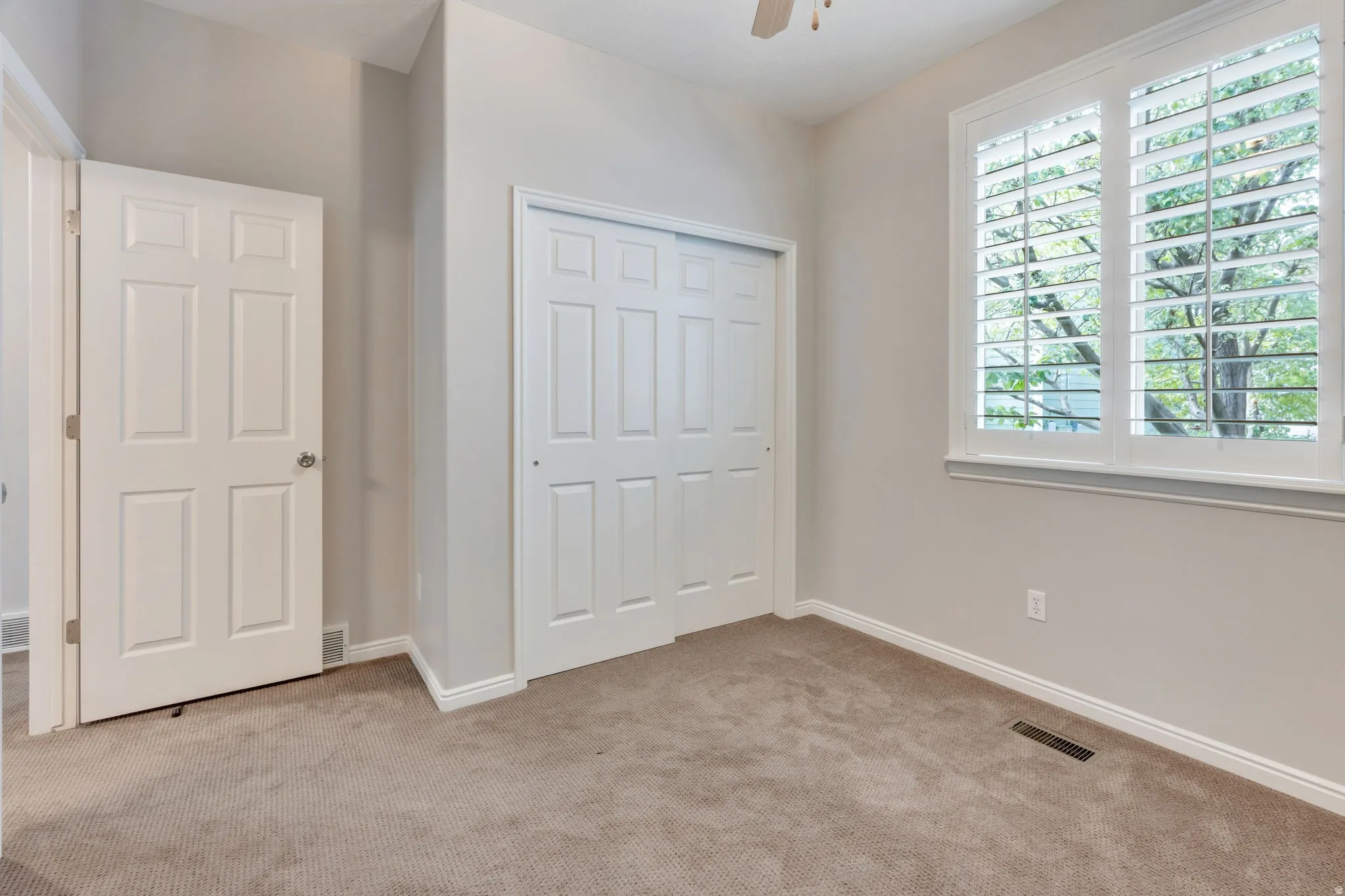 Neutral-toned carpeting, white baseboards, and a white six-panel interior door