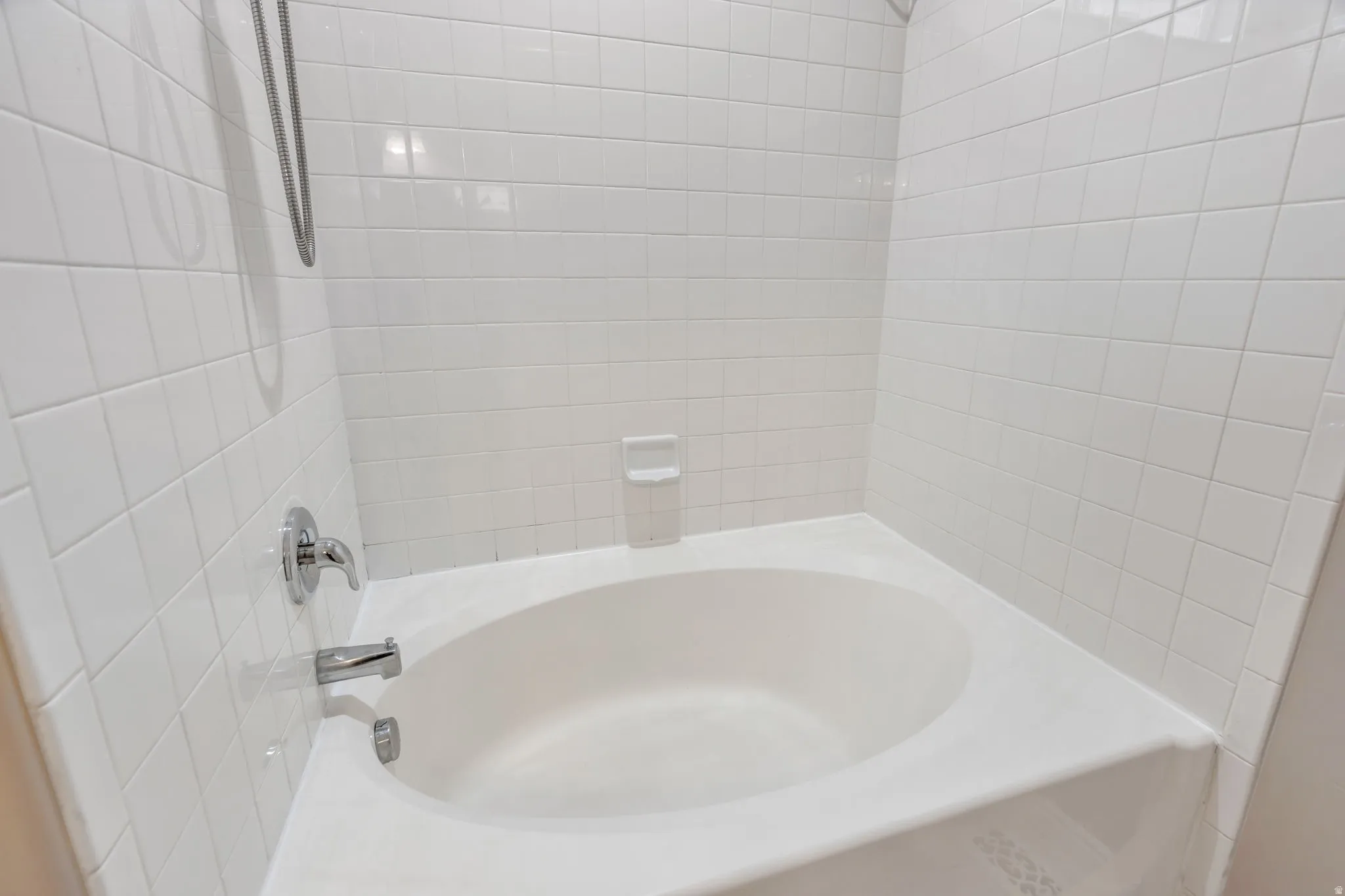 White tile surround with chrome fixtures and an integrated bathtub