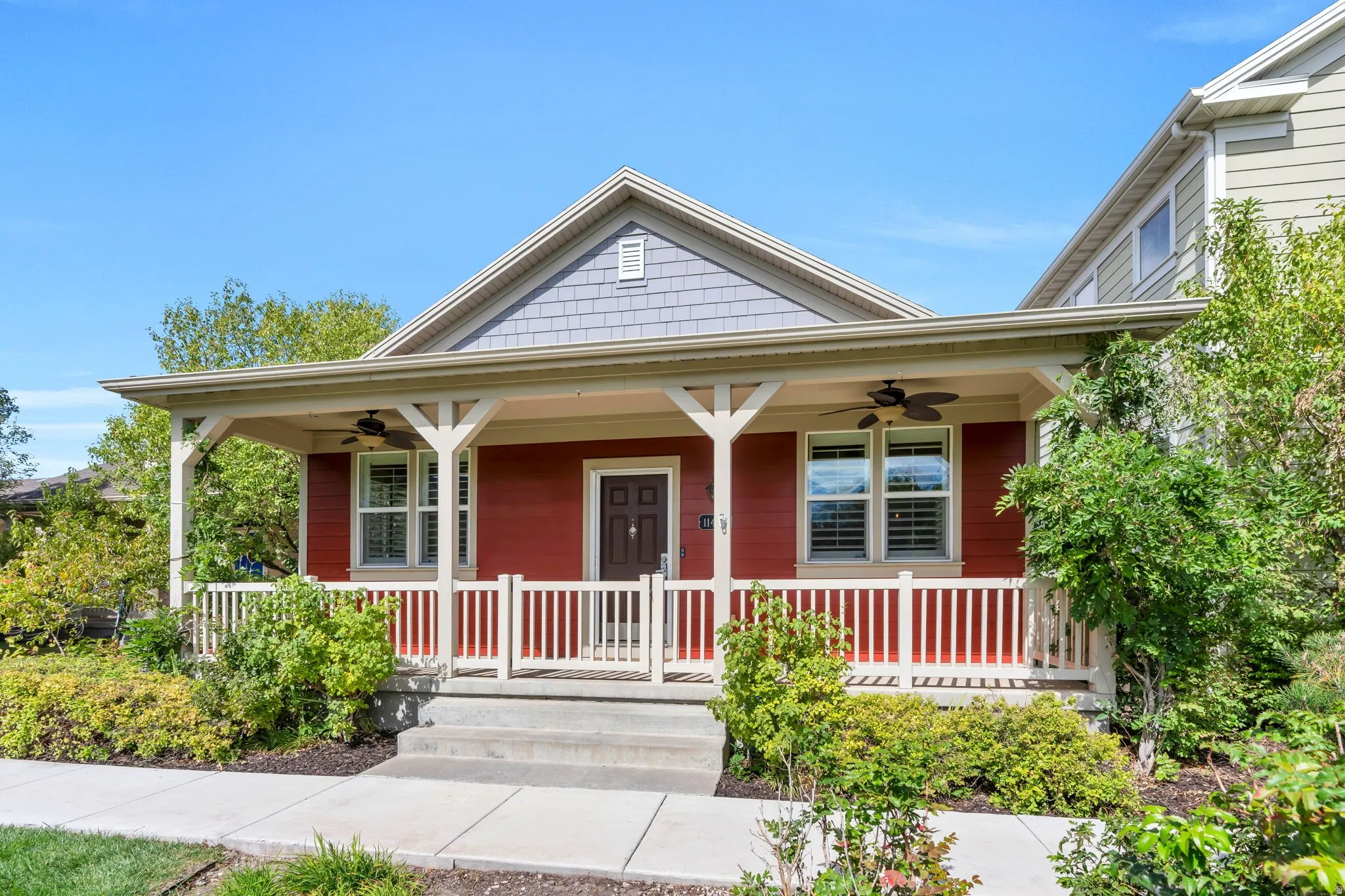 Inviting front porch with a wood railing, red siding, and decorative wood pillars
