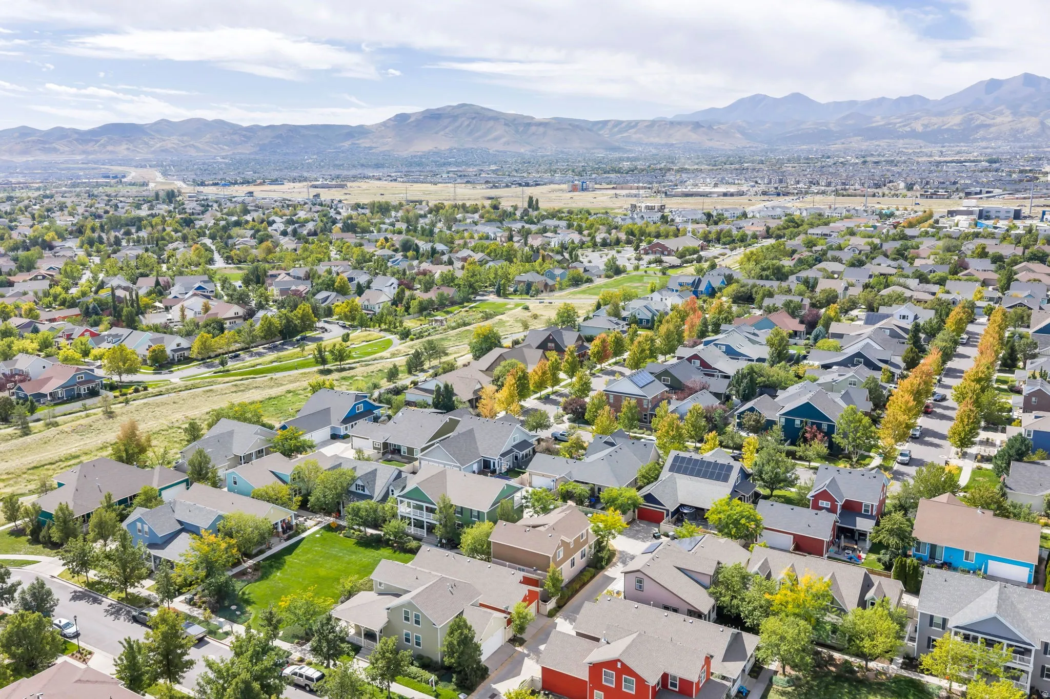 Residential neighborhood with varied architectural styles, mature trees, and mountainous background