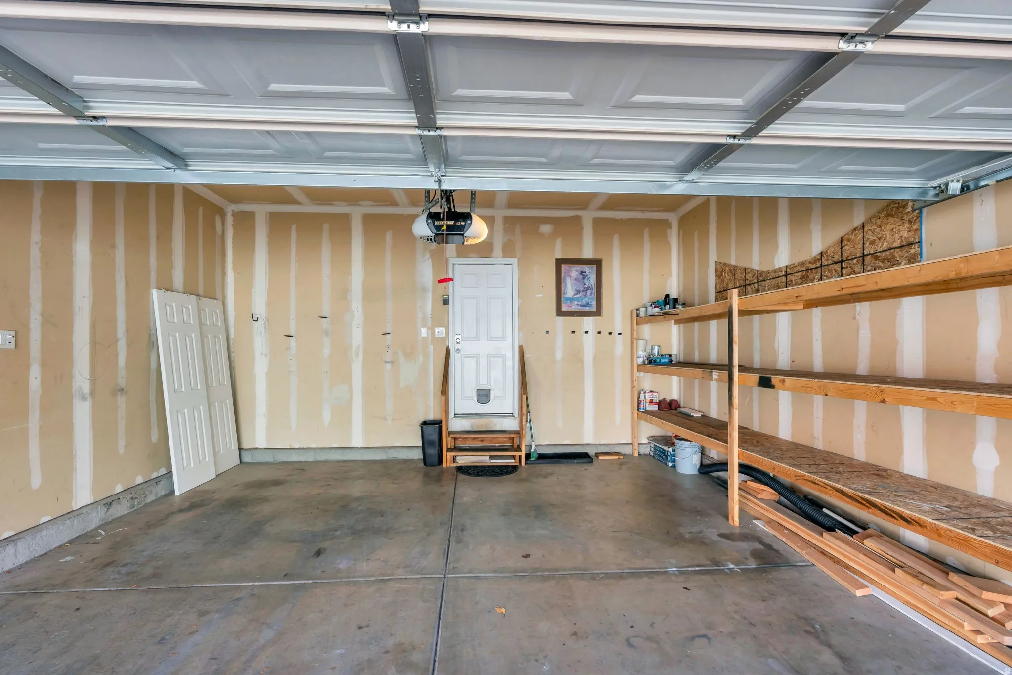 Garage space with concrete flooring, overhead garage door, and built-in shelving