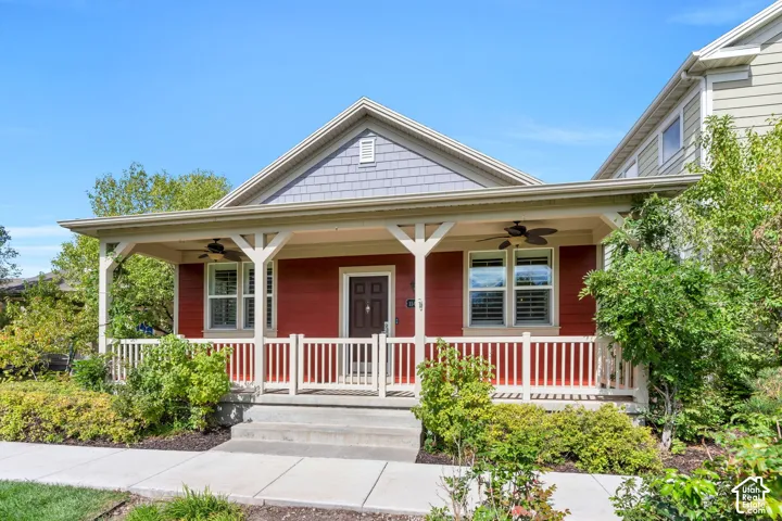 Inviting front porch with a wood railing, red siding, and decorative wood pillars