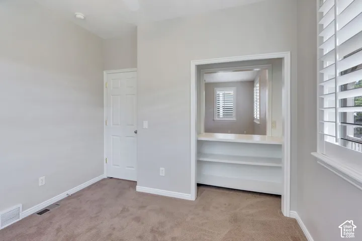 Neutral wall color, shuttered windows, built-in shelving, carpet flooring, and a white door