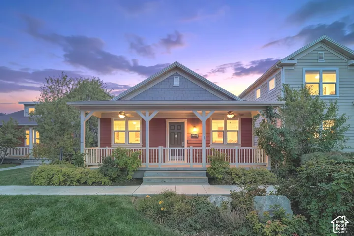 Red siding exterior with gray shake accent, covered front porch with white railing, and landscaped front yard