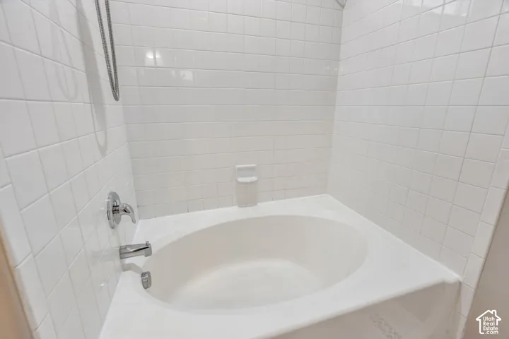 White tile surround with chrome fixtures and an integrated bathtub