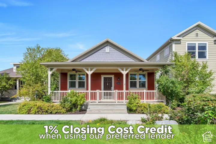 Gable roofline with gray shingles, red siding, covered front porch, white railings, and mature landscaping