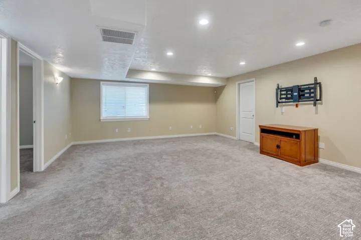 Recessed lighting illuminates the carpeted flooring and light-toned walls