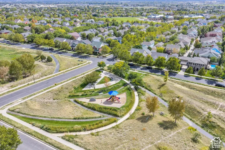 Neighborhood setting featuring mature trees, paved streets, a community park with playground equipment, and residential homes