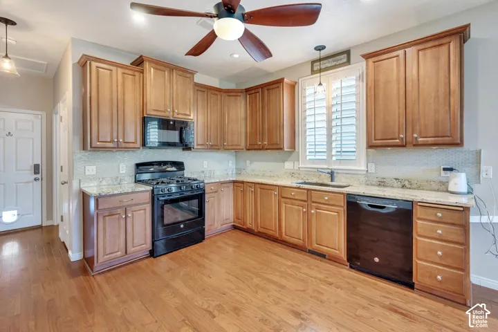 Kitchen featuring wood-finish flooring, wood cabinetry, stone countertops, a tile backsplash, and a ceiling fan with integrated lighting