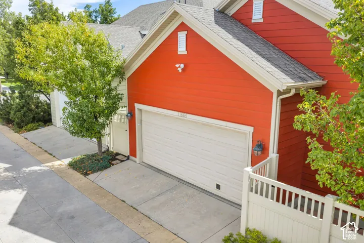 Red siding exterior with white trim, a single garage door, and outdoor wall sconces
