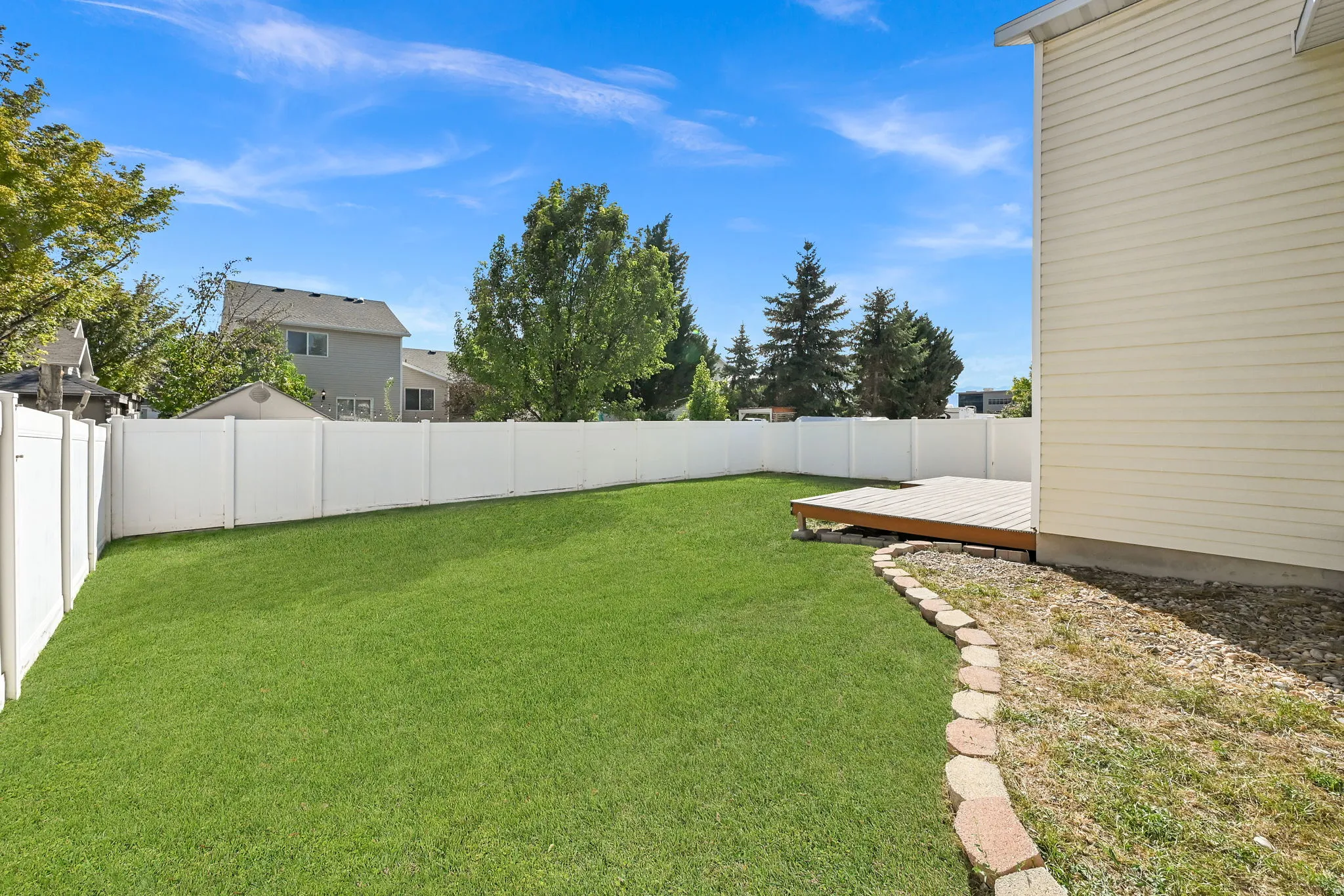 Expansive green lawn with a privacy fence, complemented by a raised wood deck
