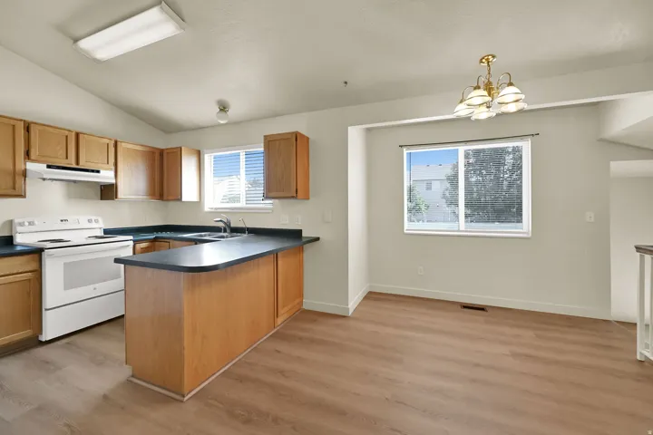 Kitchen with wood-finish flooring, vaulted ceiling, and ample cabinetry