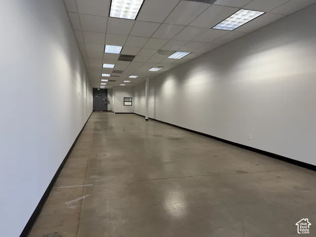 Expansive open-concept interior featuring smooth concrete flooring, high ceilings with recessed grid lighting, and neutral wall finishes