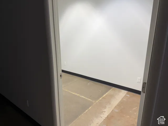 Interior room featuring smooth-finish walls, neutral paint, concrete flooring, and solid-core door frame