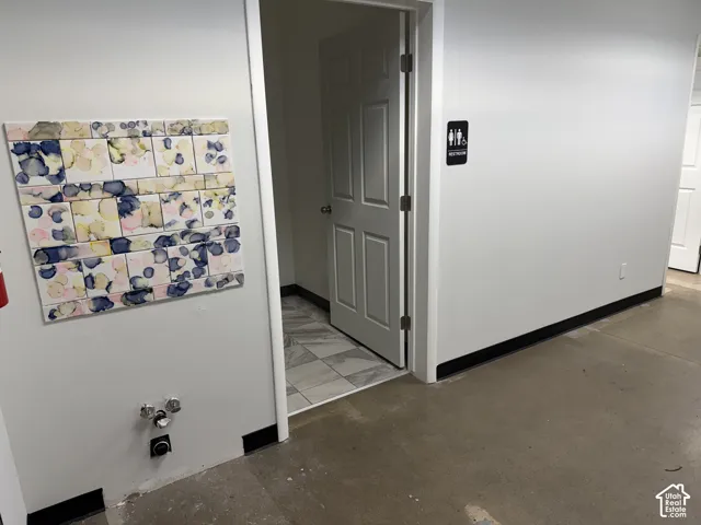 Polished concrete flooring, interior door with metal hardware, tiled wall feature, and smooth-finish walls