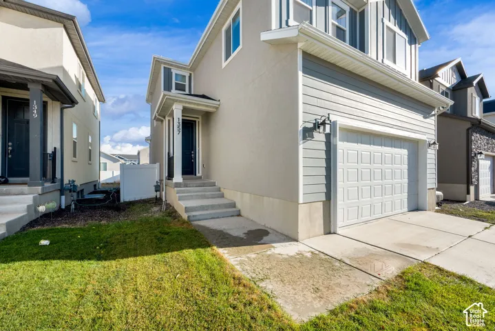Two-story exterior with a two-car garage, concrete driveway, and front entryway with concrete steps