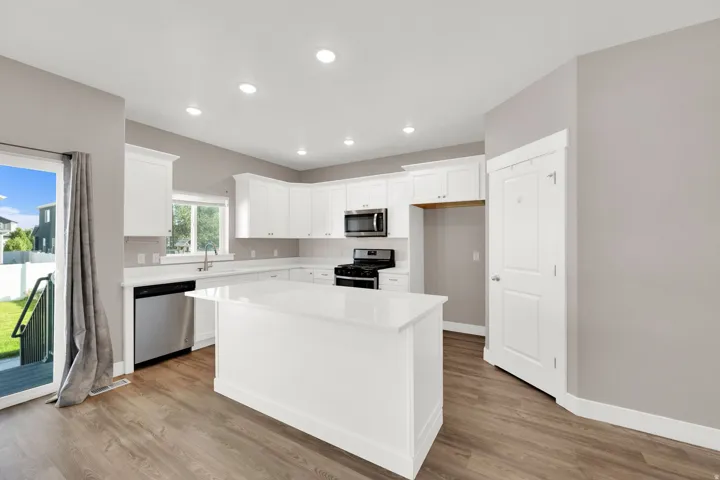 Kitchen featuring white cabinetry, stainless steel appliances, a center island with a solid surface countertop, wood-finish flooring, and recessed lighting