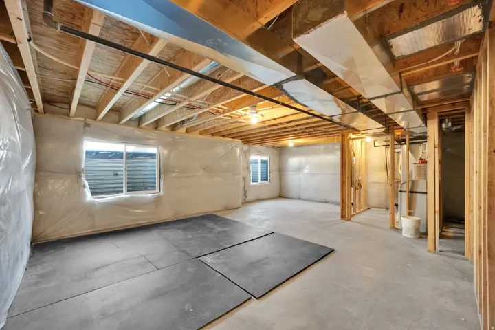 Unfinished basement with exposed ceiling joists, concrete flooring, and multiple egress windows