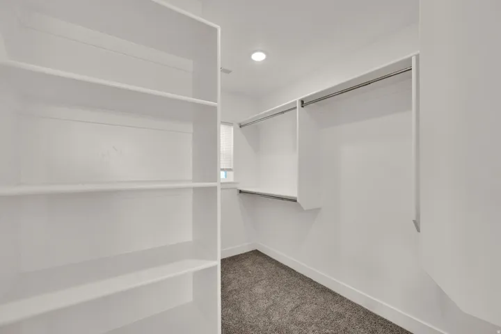 Built-in shelving, hanging rods, recessed lighting, and carpeted flooring