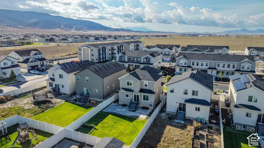 Expansive residential development featuring detached homes with fenced yards, multi-family structures, and mountain scenery