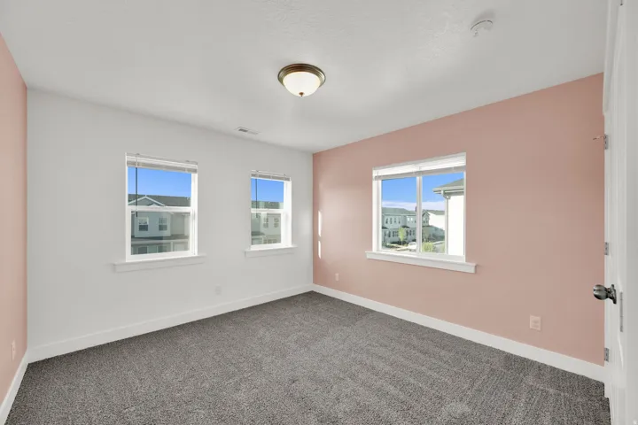 Plush grey carpeting, three bright windows, and a flush mount light fixture