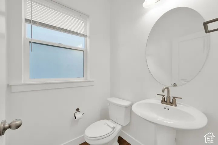 Pedestal sink with a brushed nickel faucet, an oval mirror, and a window with blinds