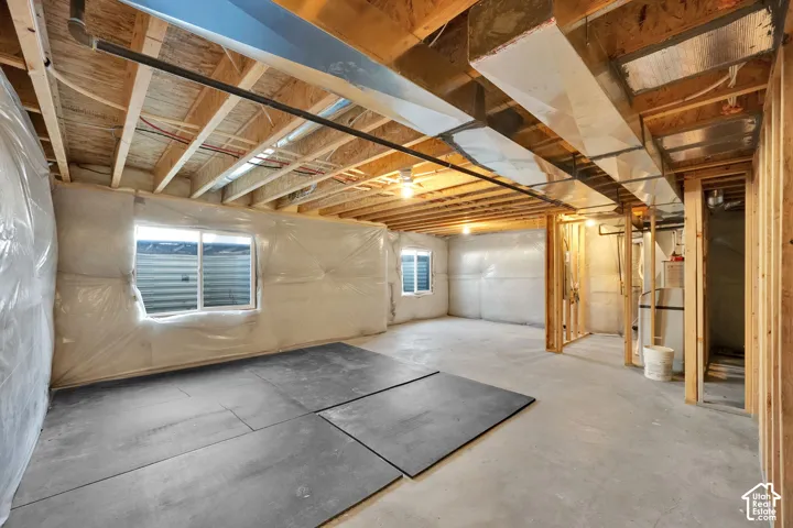Unfinished basement with exposed ceiling joists, concrete flooring, and multiple egress windows