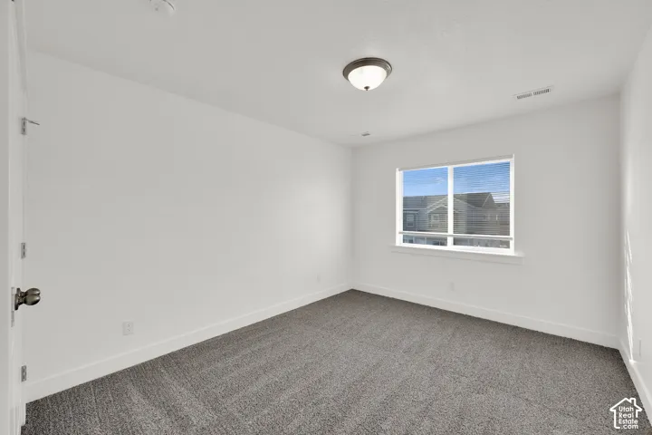 Bright room featuring a single window, overhead flush-mount light fixture, and gray carpeting
