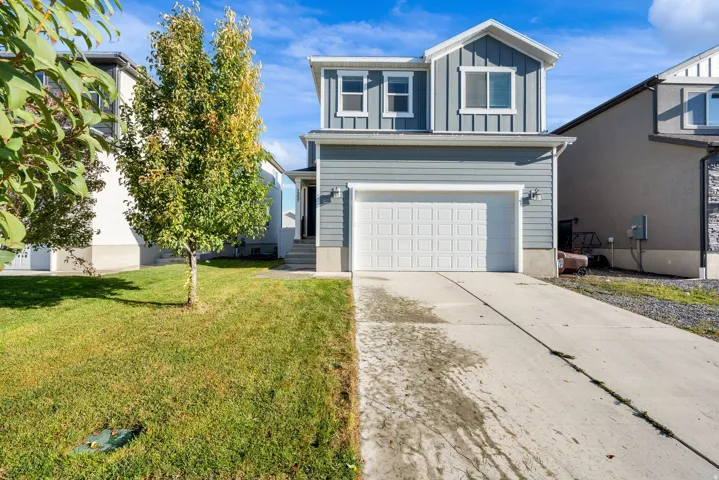 Two-story residence featuring light blue siding with white trim, a two-car garage, and a concrete driveway